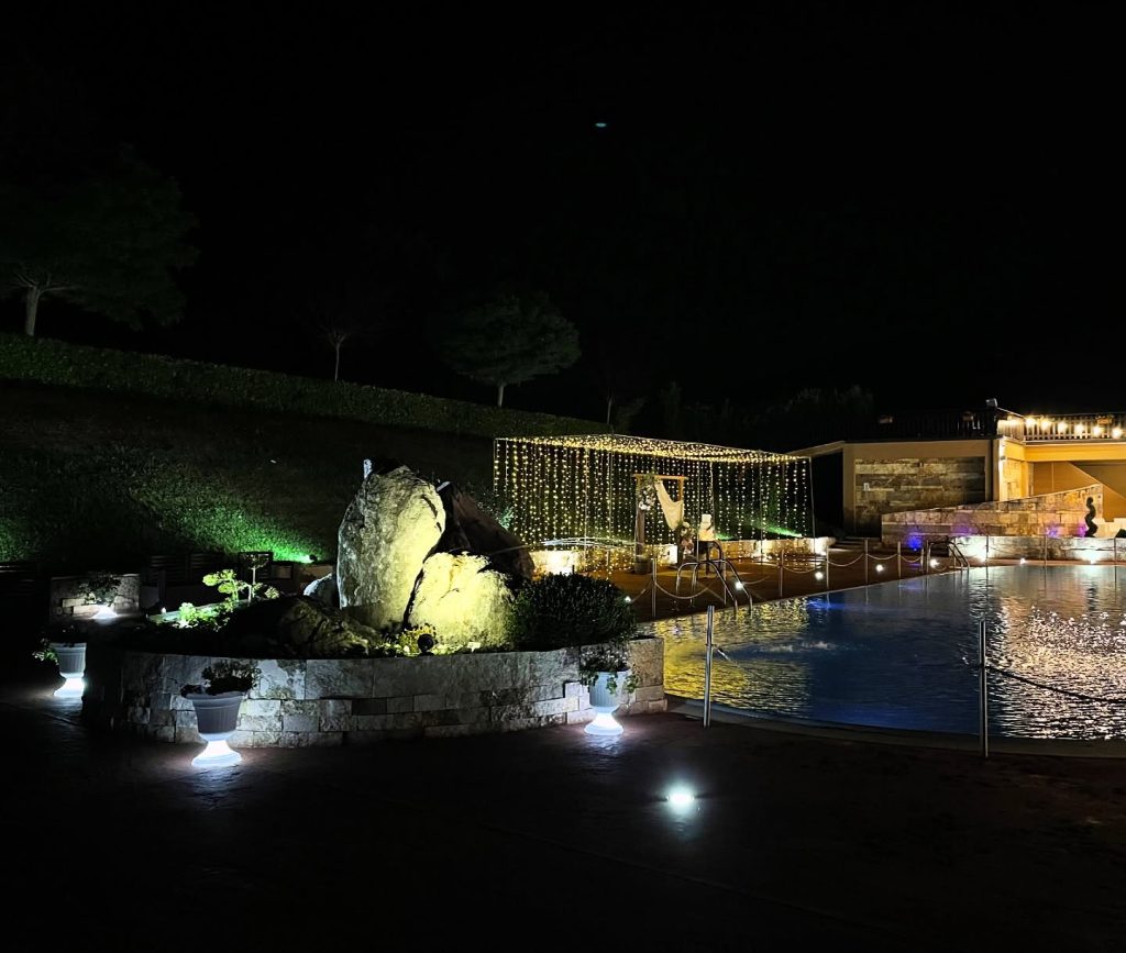 Piscina e area eventi illuminate durante una cerimonia serale all'Hotel Kiris.